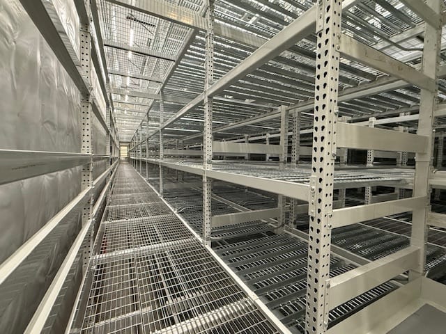 Long aisle between multi-level archive box storage shelving with wire mesh walkways